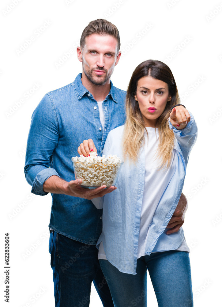 Sticker young couple in love eating popcorn over isolated background pointing with finger to the camera and 