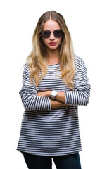 Naklejka premium Young beautiful blonde woman wearing sunglasses over isolated background skeptic and nervous, disapproving expression on face with crossed arms. Negative person.