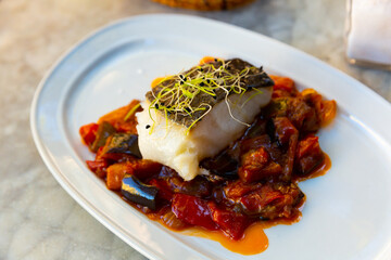 Healthy dinner, cod confit with ratatouille in tomato sauce