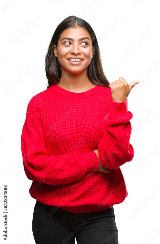 Wall mural Young beautiful arab woman wearing winter sweater over isolated background smiling with happy face looking and pointing to the side with thumb up.