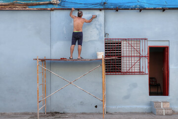 Fototapeta premium A man painting facade of a building in blue color in Cuba Havana