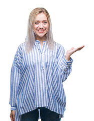 Young blonde woman over isolated background smiling cheerful presenting and pointing with palm of hand looking at the camera.