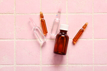Ampules with bottle with medicines on pink tile background