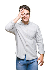Fototapeta premium Young handsome man wearing glasses over isolated background doing ok gesture with hand smiling, eye looking through fingers with happy face.