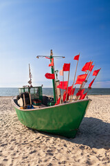 Fishing boat on the beach in a sunny day with red flags.
Łódź rybacka na plaży w słoneczny dzień z czerwonymi flagami. Międzyzdroje. Polska