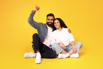 Middle Eastern Couple Showing House Key Sitting Over Yellow Background