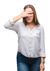 Young caucasian beautiful business woman wearing glasses over isolated background peeking in shock covering face and eyes with hand, looking through fingers with embarrassed expression.