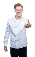 Young handsome blond man smiling friendly offering handshake as greeting and welcoming. Successful business.
