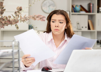 Fototapeta na wymiar Sad woman bookkeeper doing paperwork during workday in office.