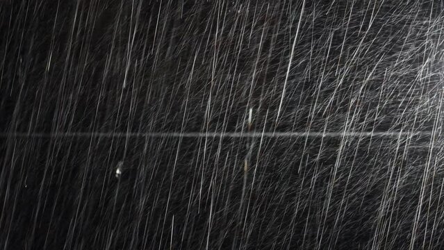 Illuminated raindrops on a dark background with hanging electric cable