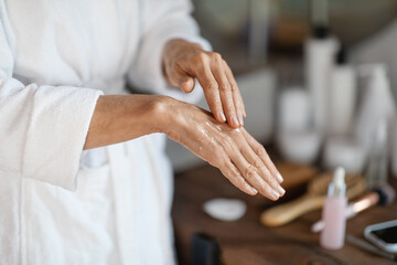 Obraz na płótnie Canvas Dry Skin Treatments. Mature woman applying anti-aging serum on hands at home