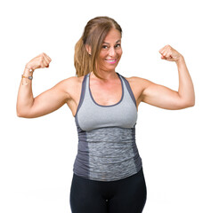 Beautiful middle age woman wearing sport clothes over isolated background showing arms muscles smiling proud. Fitness concept.