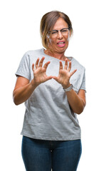 Middle age senior hispanic woman wearing glasses over isolated background disgusted expression, displeased and fearful doing disgust face because aversion reaction. With hands raised