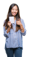 Young asian woman holding notebook over isolated background happy with big smile doing ok sign, thumb up with fingers, excellent sign