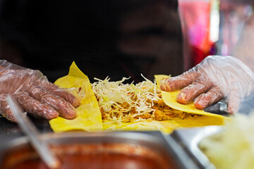 male hands in disposable gloves roll vegetarian shawarma into corn pita bread. street food