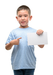 Dark haired little child holding a blank card very happy pointing with hand and finger