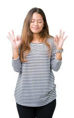 Young beautiful brunette woman wearing stripes sweater over isolated background relax and smiling with eyes closed doing meditation gesture with fingers. Yoga concept.