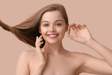 Beautiful young woman with ampule on beige background. Hair loss treatment
