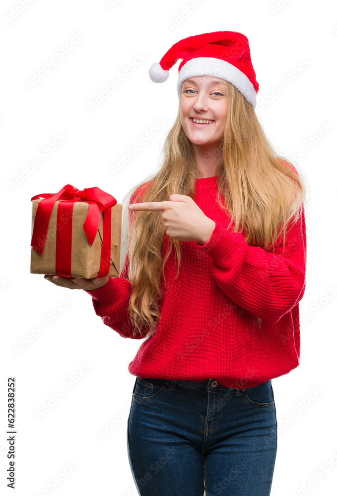 Sticker blonde teenager woman wearing santa claus hat very happy pointing with hand and finger