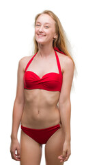 Obraz premium Blonde teenager woman wearing red bikini with a happy and cool smile on face. Lucky person.