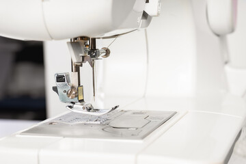 Modern white sewing machine presser foot closeup, macro. Sewing equipment, work tool for atelier business, manufacturing, occupation.