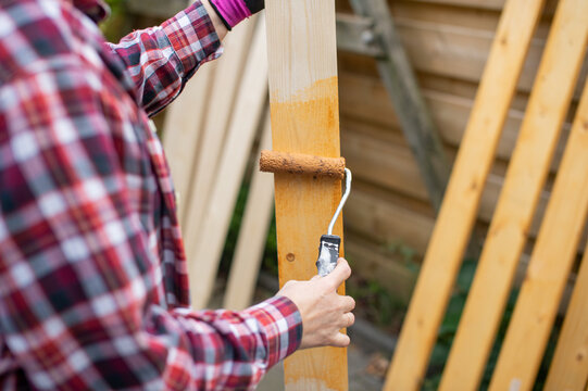 Man painting wooden fence