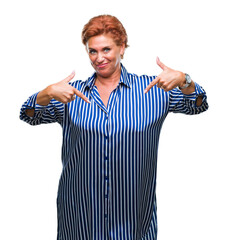 Atrractive senior caucasian redhead woman over isolated background looking confident with smile on face, pointing oneself with fingers proud and happy.