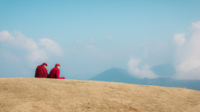 Two Buddhist monks sitting together under blue sky