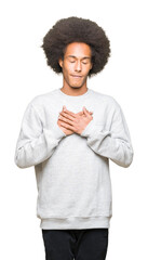 Young african american man with afro hair wearing sporty sweatshirt smiling with hands on chest with closed eyes and grateful gesture on face. Health concept.