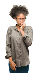 Young afro american woman wearing glasses over isolated background looking stressed and nervous with hands on mouth biting nails. Anxiety problem.