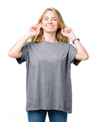 Fototapeta premium Beautiful young woman wearing oversize casual t-shirt over isolated background Smiling pulling ears with fingers, funny gesture. Audition problem