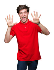 Young handsome man wearing red t-shirt over isolated background showing and pointing up with fingers number ten while smiling confident and happy.