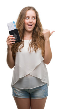 Young blonde woman holding passport of canada and boarding pass pointing and showing with thumb up to the side with happy face smiling