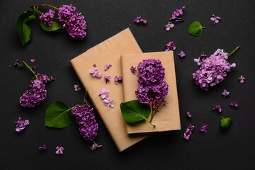 Beautiful lilac flowers and books on dark background