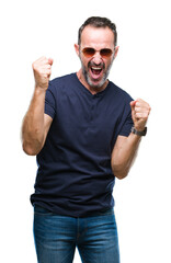 Naklejka premium Middle age hoary senior man wearing sunglasses over isolated background very happy and excited doing winner gesture with arms raised, smiling and screaming for success. Celebration concept.