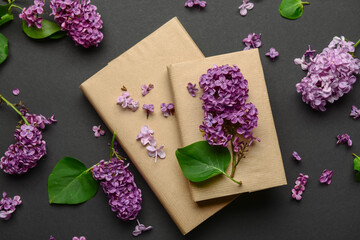 Beautiful lilac flowers and books on dark background