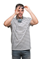 Handsome young man wearing headphones doing ok gesture with hand smiling, eye looking through fingers with happy face.