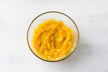 Glass bowl of pumpkin filling with cheese on a light blue background, top view. Cooking pumpkin casserole or pie