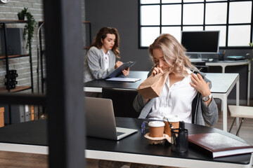 Young woman with paper bag having panic attack in office