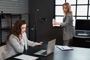 Woman giving water to her colleague who is having panic attack in office