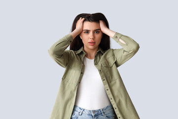 Young woman having panic attack on light background