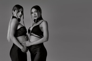 Photo of elegant pregnant young women, twins sisters. Studio shot of a ladies who are expecting babies.