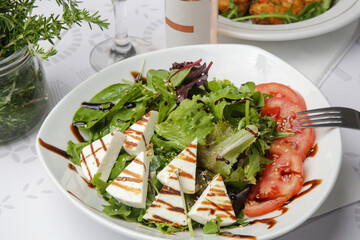 Traditional greek salad in the plate - lettuce, feta cheese and tomato slices with olive oil	