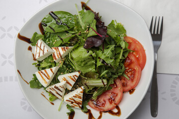 Traditional greek salad in the plate - lettuce, feta cheese and tomato slices with olive oil	