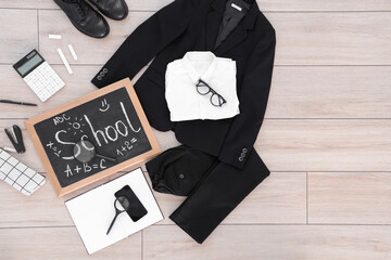 Composition with stylish school uniform, eyeglasses, chalkboard, mobile phone and stationery on wooden background