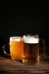 Mugs of cold beer on wooden table