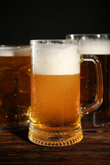 Mugs of cold beer on wooden table, closeup