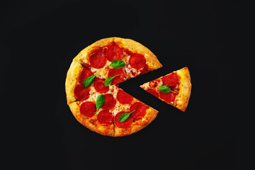 Fresh pepperoni pizza with a cut off piece on a black background..