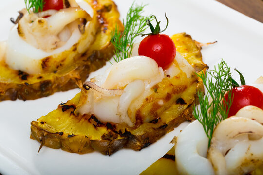 Sepia fried on a grill with pineapple and cherry tomatoes is tasty dish in the kitchen.