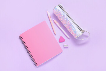 Notebook with pencil case and different stationery on lilac background